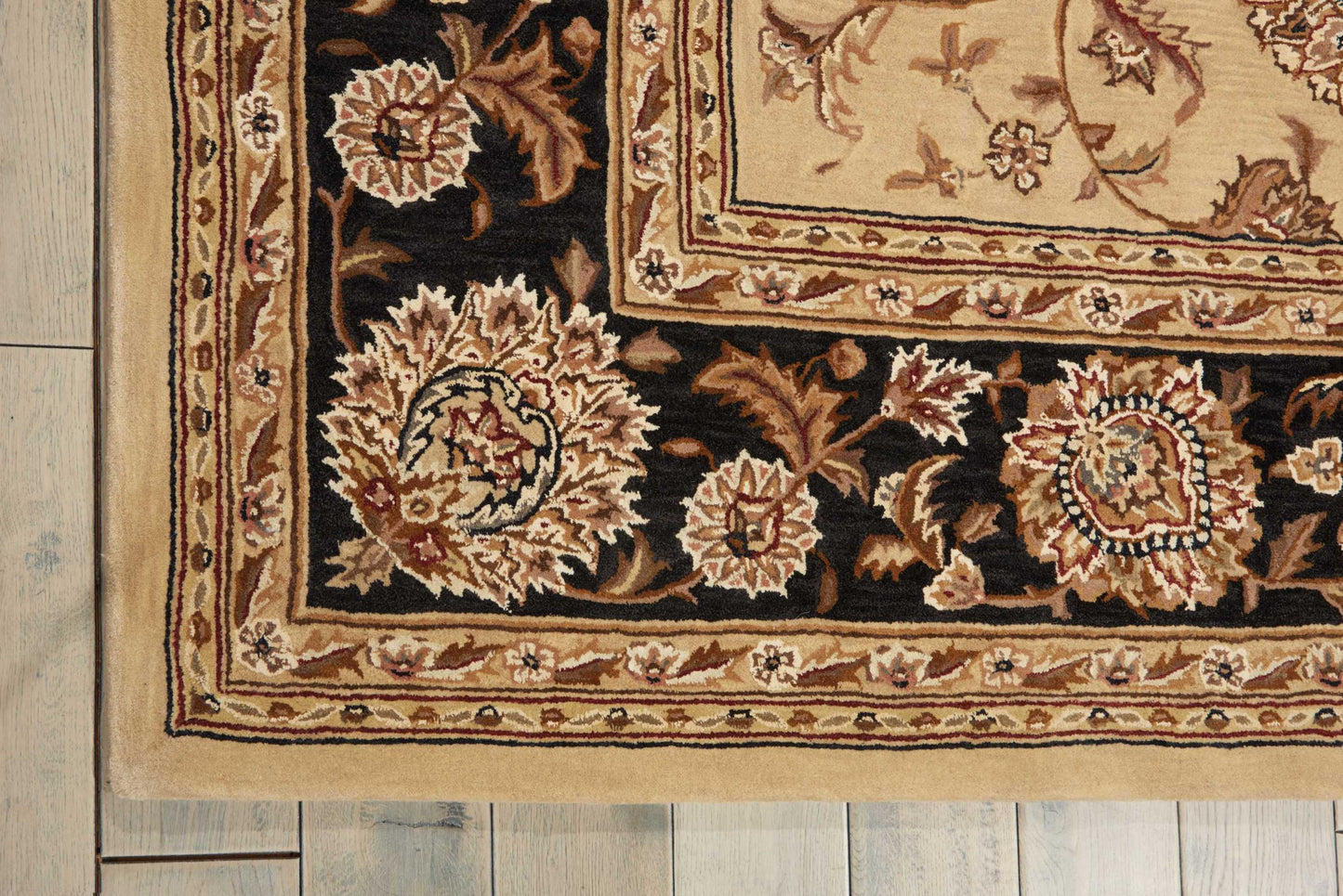 Traditional oriental rug with cream borders, black field and red-tan floral motifs; wool, decorative area rug.