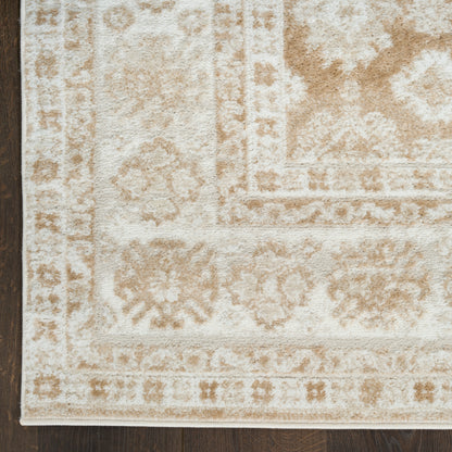 Cream and beige oriental rug with distressed floral medallions and geometric border on dark wooden floor.