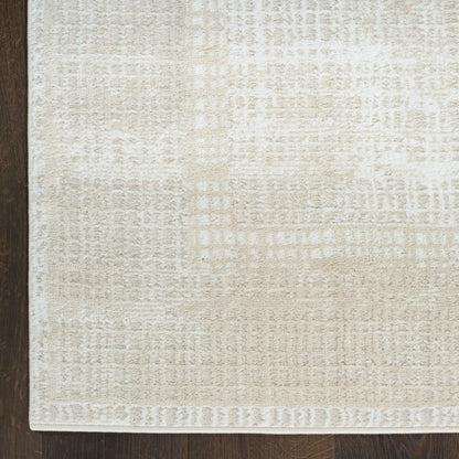 Rectangular beige area rug with a subtle geometric texture and a lighter cream border, shown on dark wood flooring.