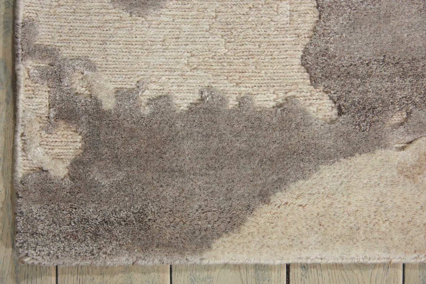 Abstract-pattern shag rug in cream, beige and taupe with a textured pile on a wooden floor.