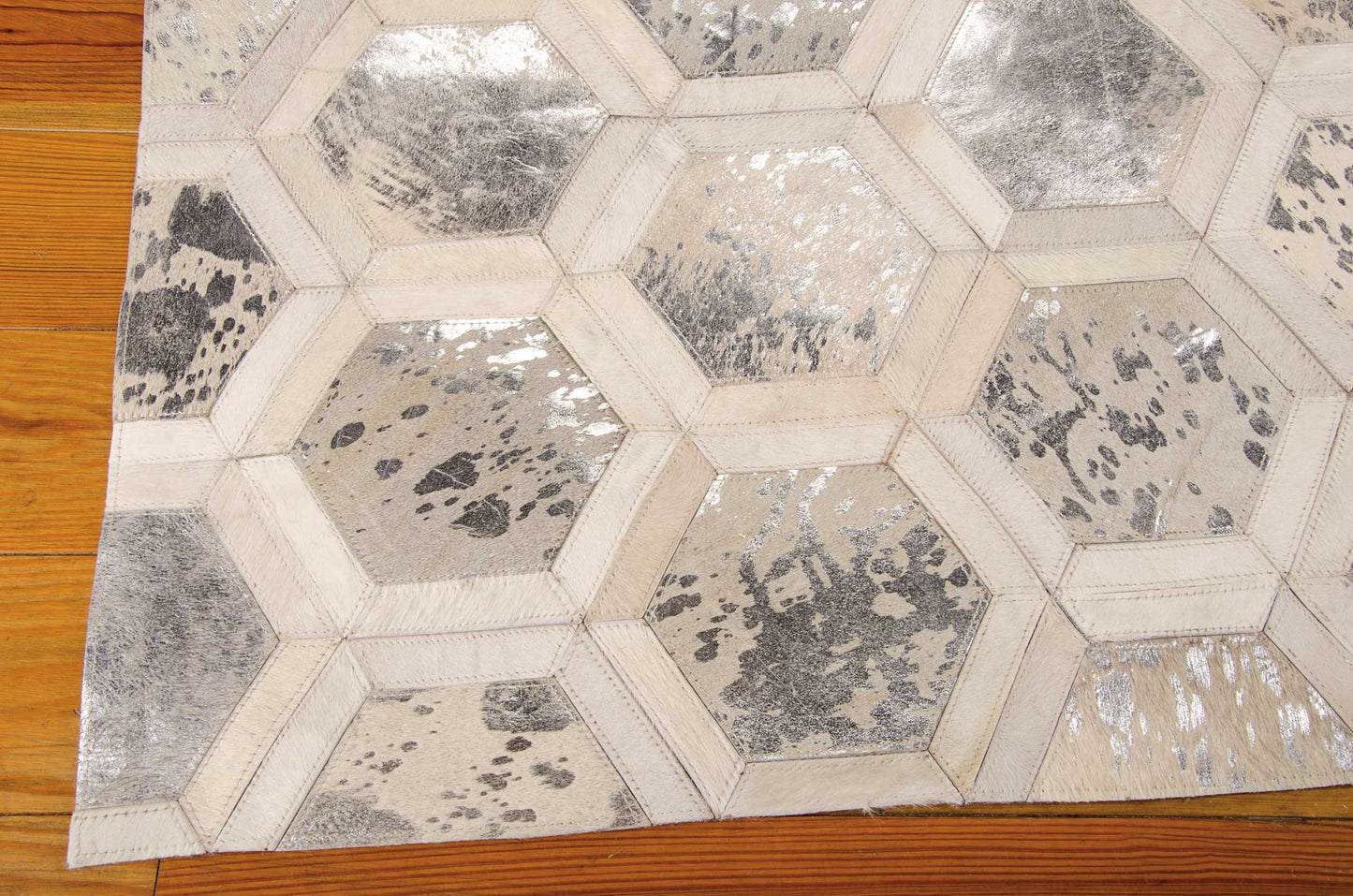Beige hexagon patterned rug with metallic silver patches; geometric contemporary floor covering.