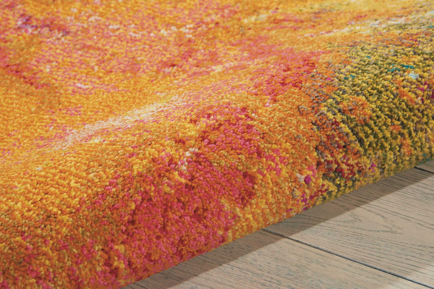 Vibrant multicolored shag rug in orange, pink, and yellow hues with a plush pile on a light wood floor.