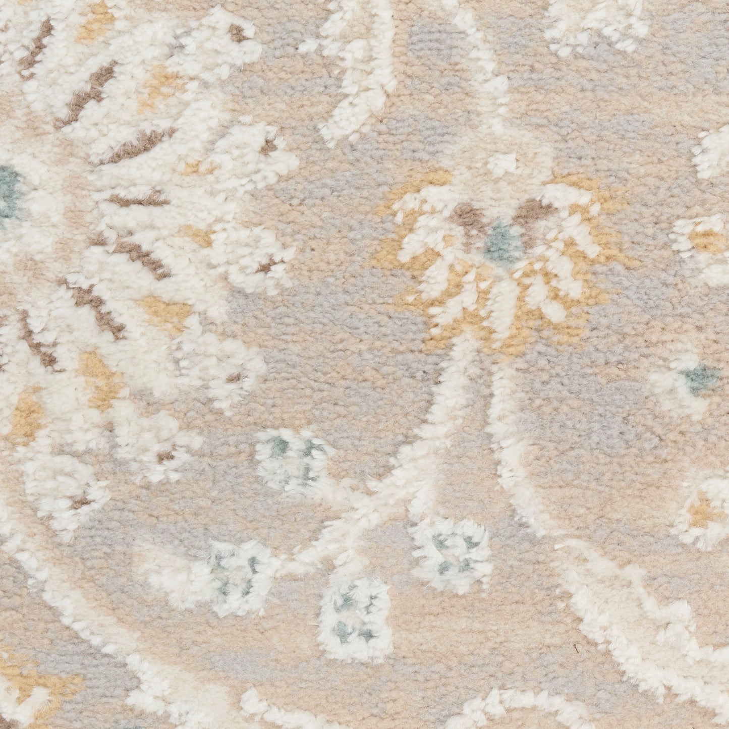 Soft beige floral patterned area rug with ivory vines, pale yellow accents and blue-green highlights; plush texture.