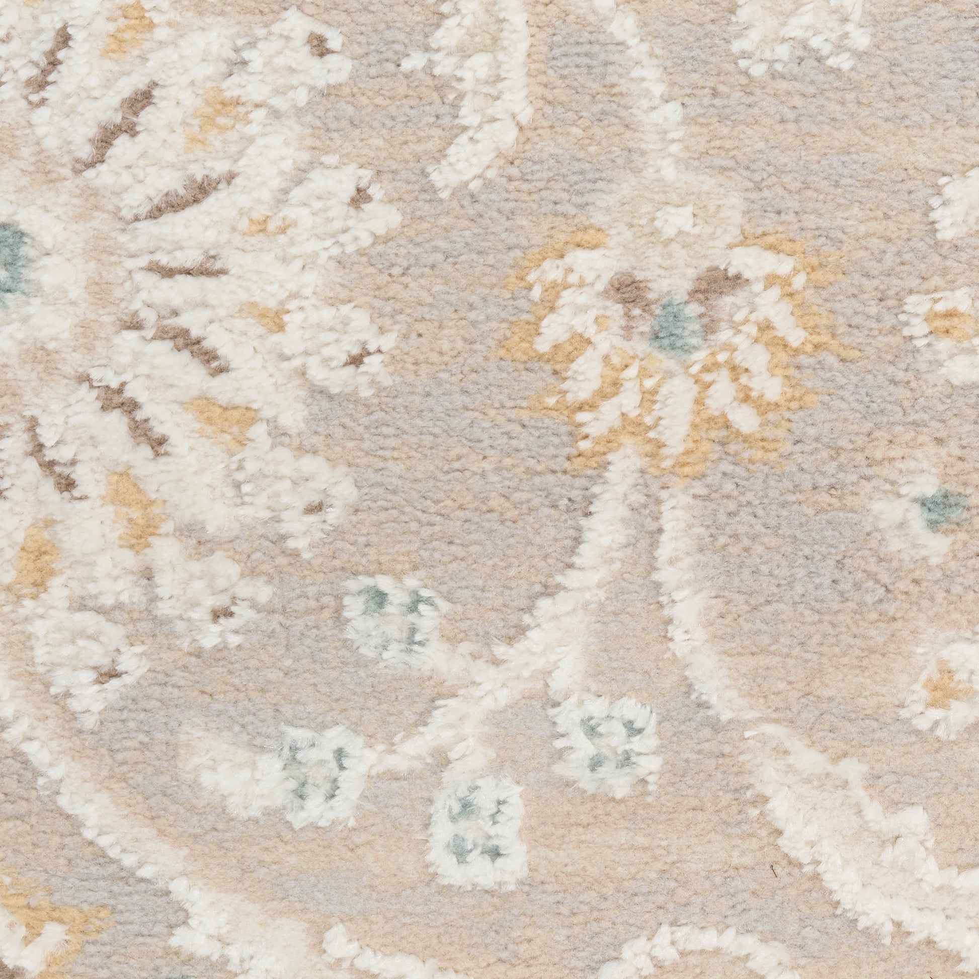 Soft beige floral patterned area rug with ivory vines, pale yellow accents and blue-green highlights; plush texture.