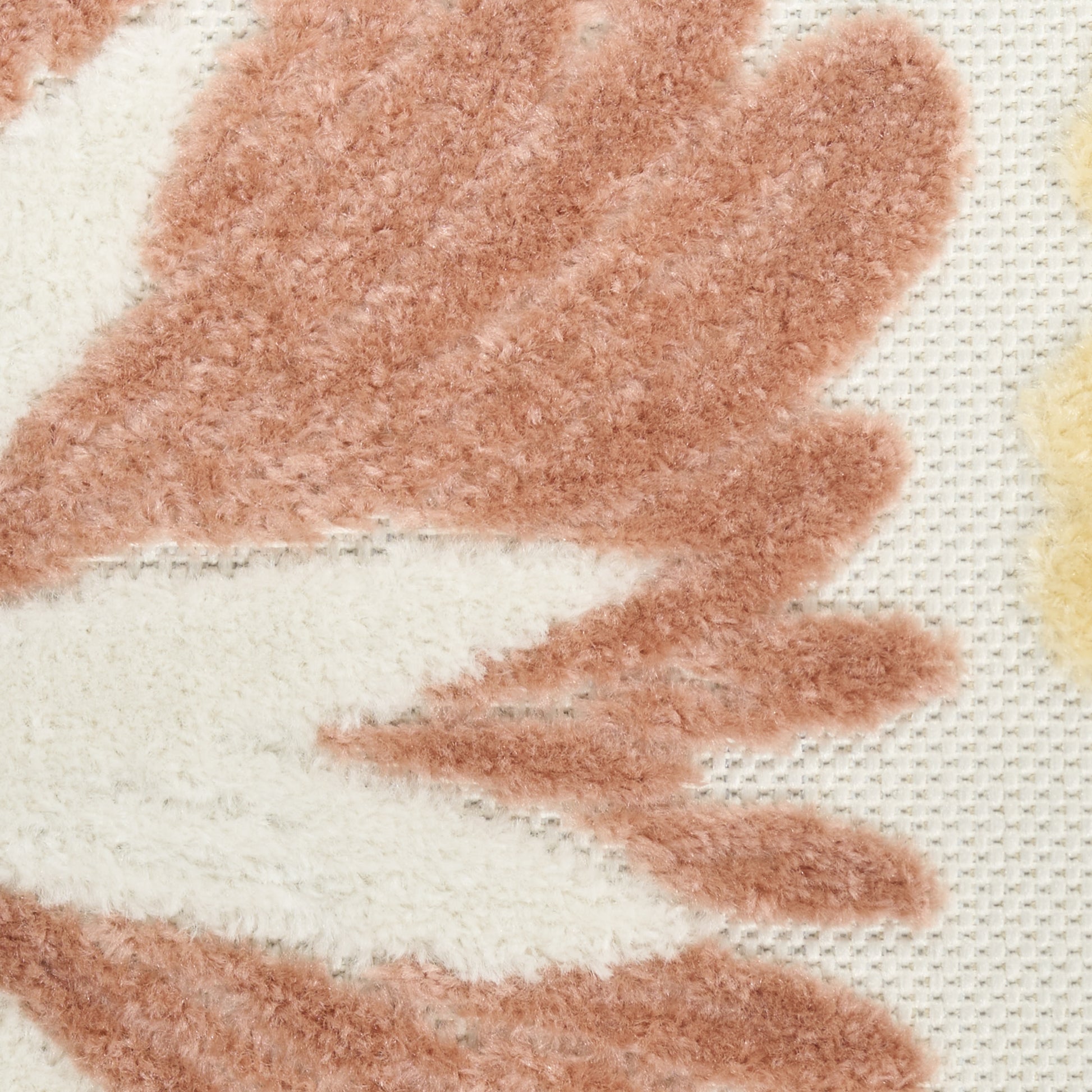 Close-up of a plush rug with cream base & peach-orange leaf pattern, soft textured pile.