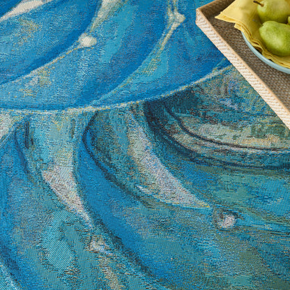 Blue abstract woven rug with teal swirls; woven texture; corner wicker tray with green pears and yellow napkin.