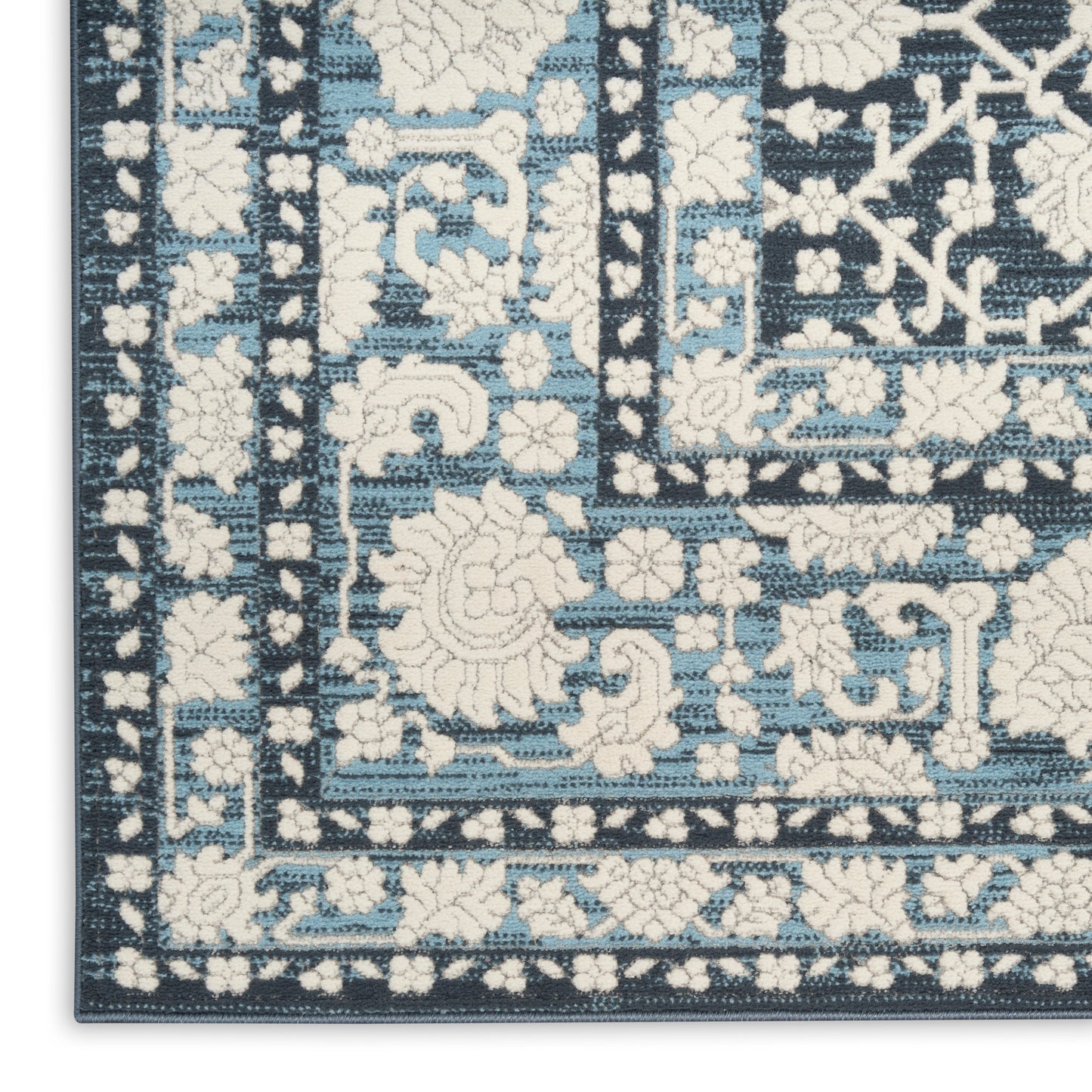 Blue and ivory Persian-inspired area rug corner with floral motifs and geometric border.
