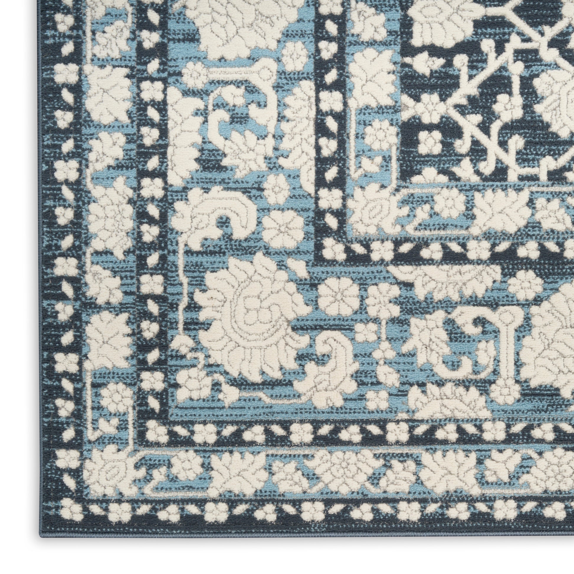 Blue and ivory Persian-inspired area rug corner with floral motifs and geometric border.