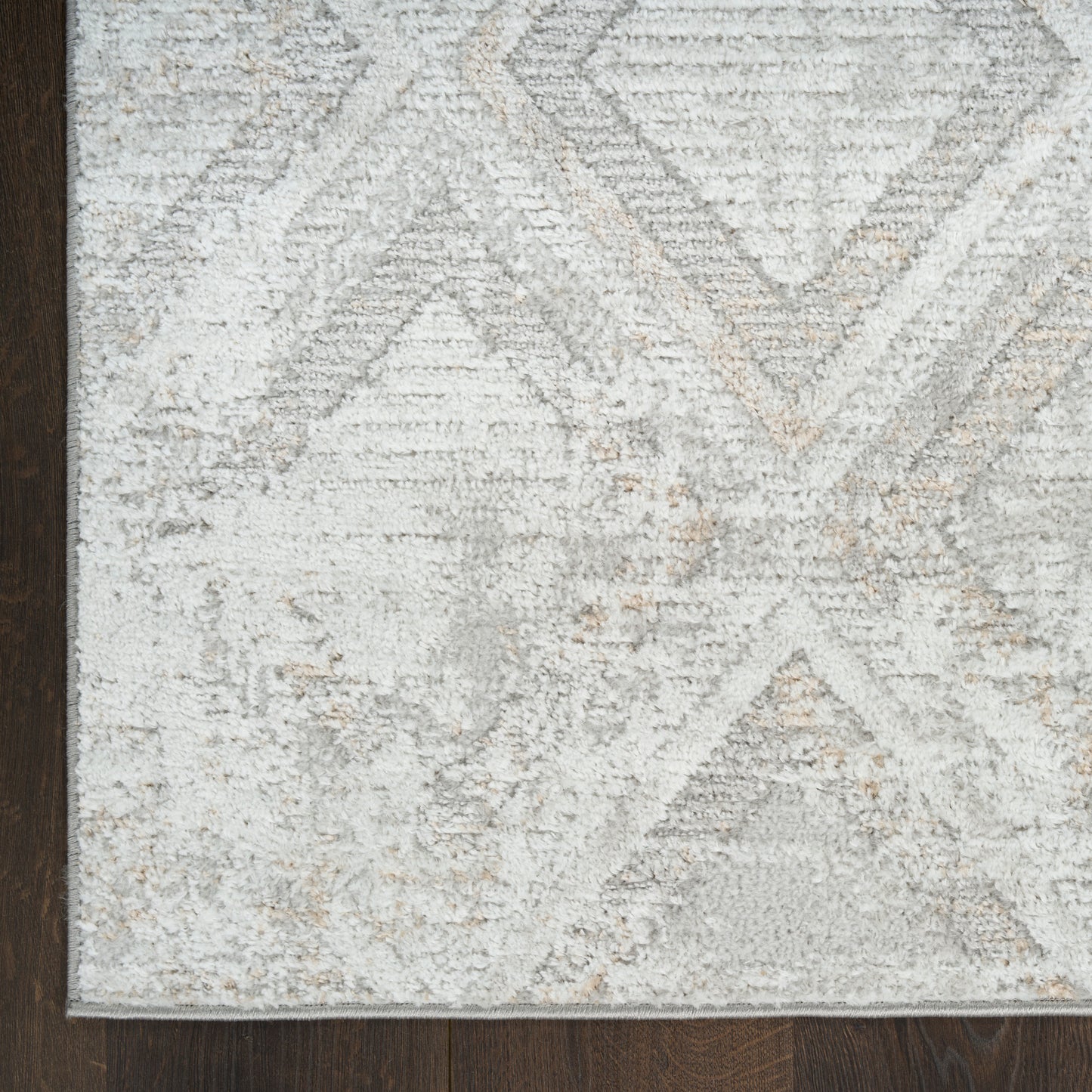 Rectangular area rug with distressed gray and beige geometric pattern on dark wood floor; soft plush pile.