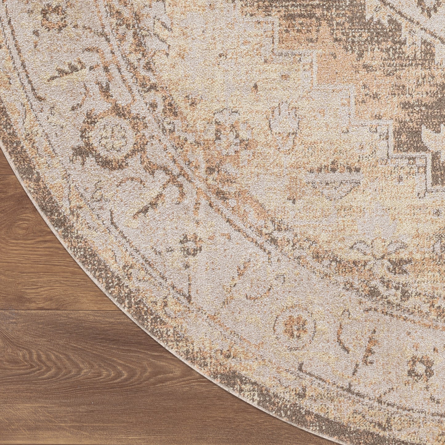 Round beige & taupe oriental rug with distressed floral medallion on hardwood floor.