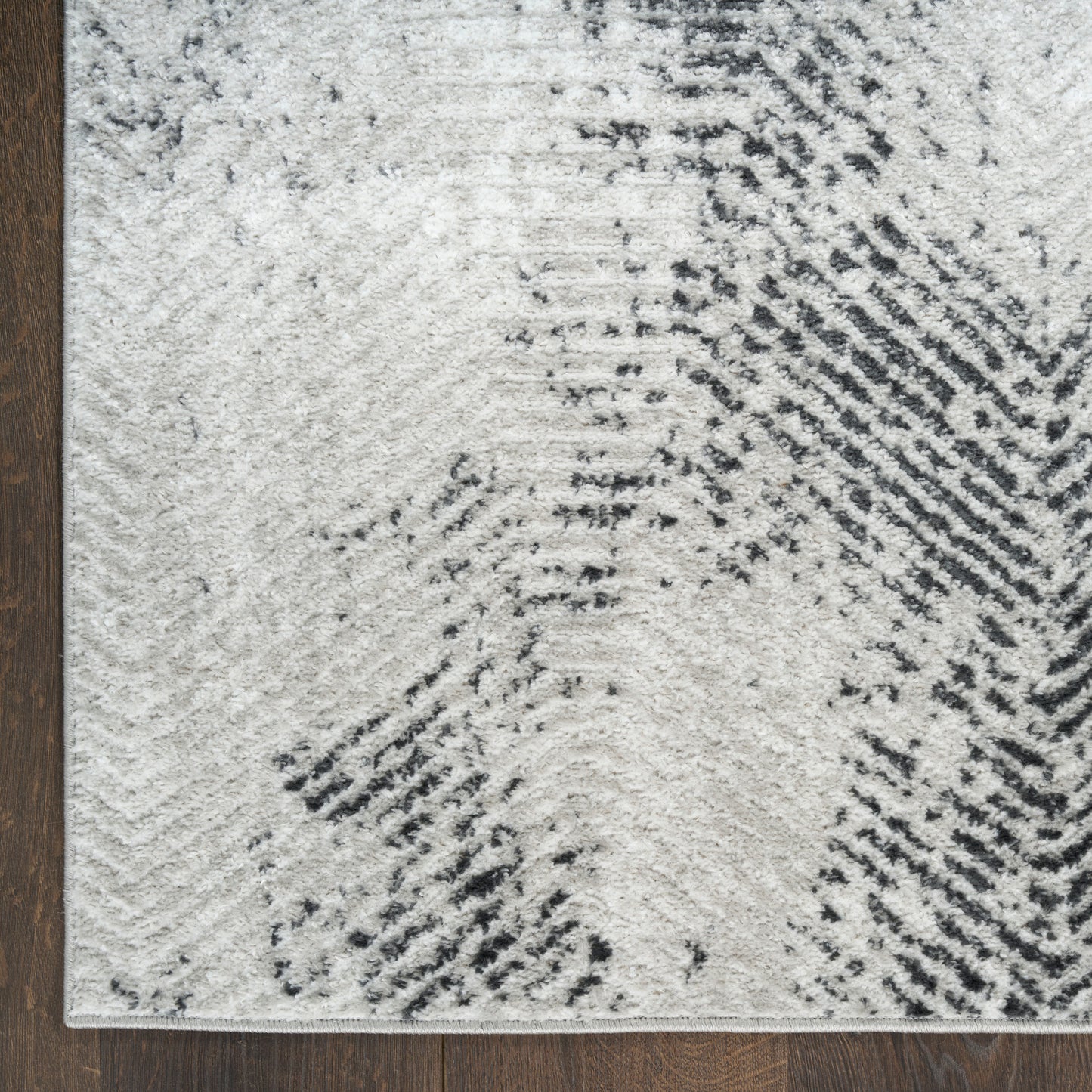 Ivory & charcoal abstract area rug with wavy geometric pattern on a dark wood floor.