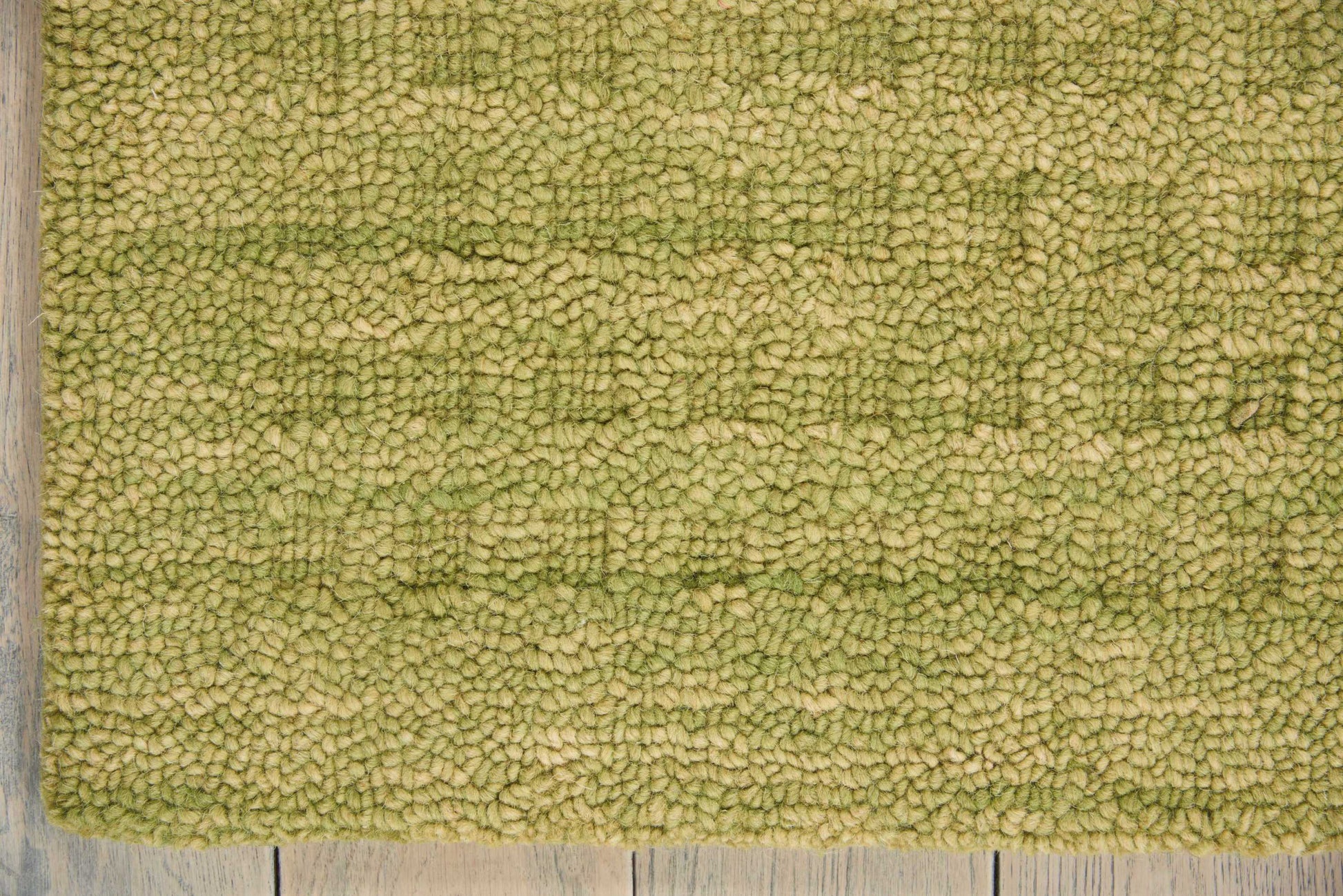 Olive green rectangular shag rug with dense plush pile, shown on a wooden floor.