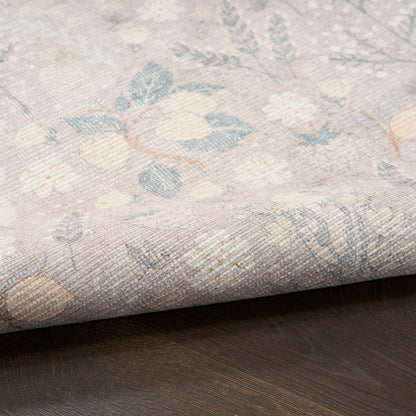 Pastel floral woven rug sample in blues, creams and pinks, rolled edge on dark wood surface.