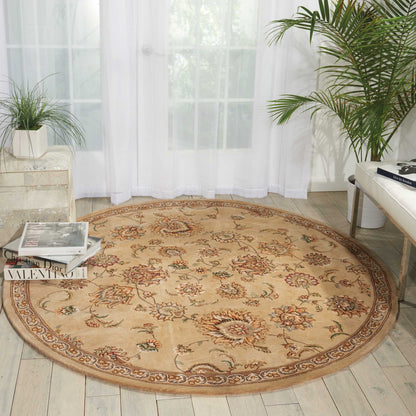 Round beige oriental rug with floral medallions and brown border on light wood floor in a bright, plant-filled living room