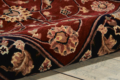 Persian-style floral rug in deep red with cream and tan flowers, wool pile, rolled edge on wood floor.