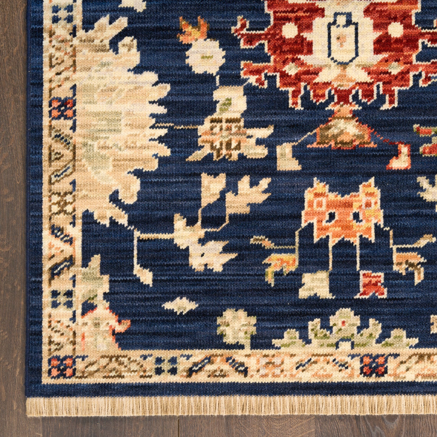 Traditional Persian-style rug with navy field, cream border, ivory and red floral motifs, and fringe along edge.