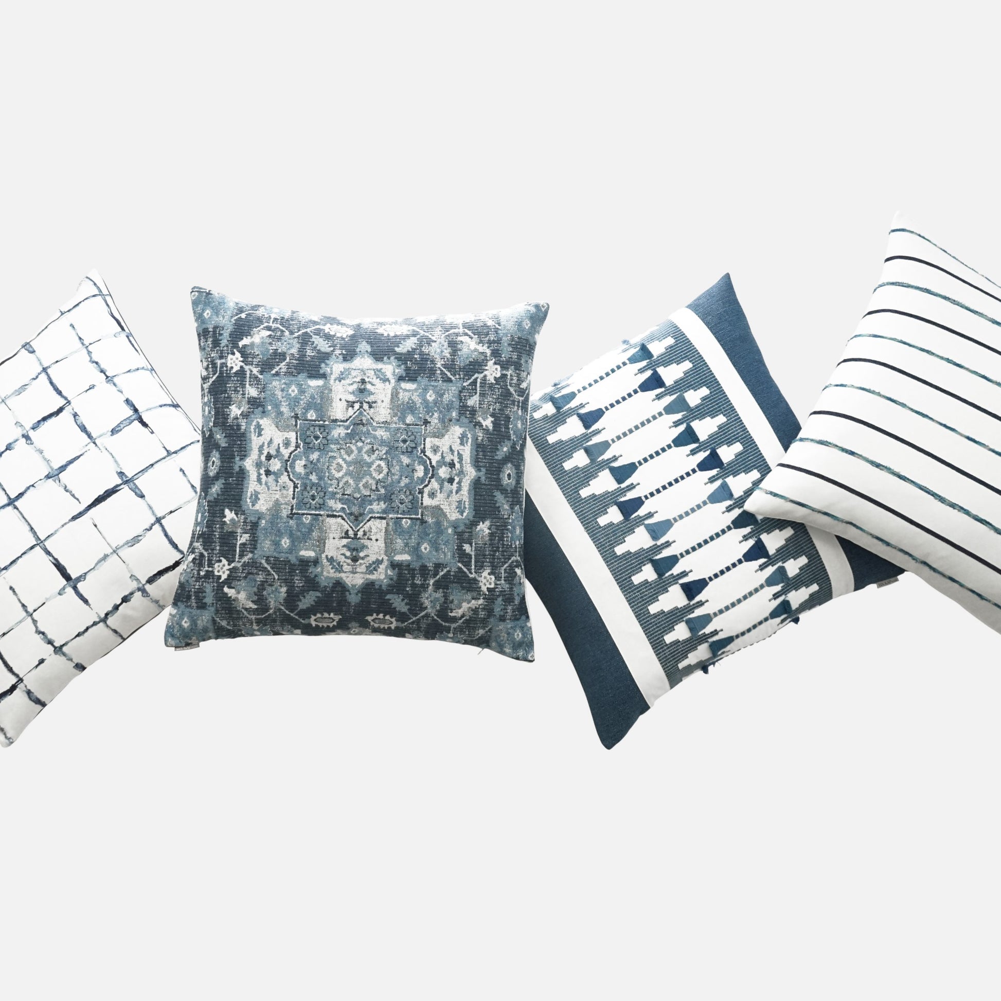 Blue and white decorative throw pillow with grid, medallion, and striped patterns arranged diagonally.