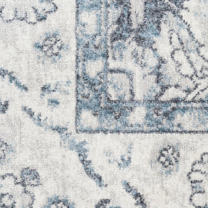 Blue-gray distressed patterned rug with floral medallion border, close-up view.