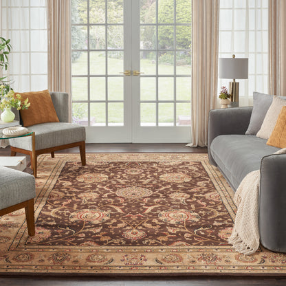Classic living room with brown oriental rug, gray sofas, orange cushions, beige throw, and French doors with sheer curtains.