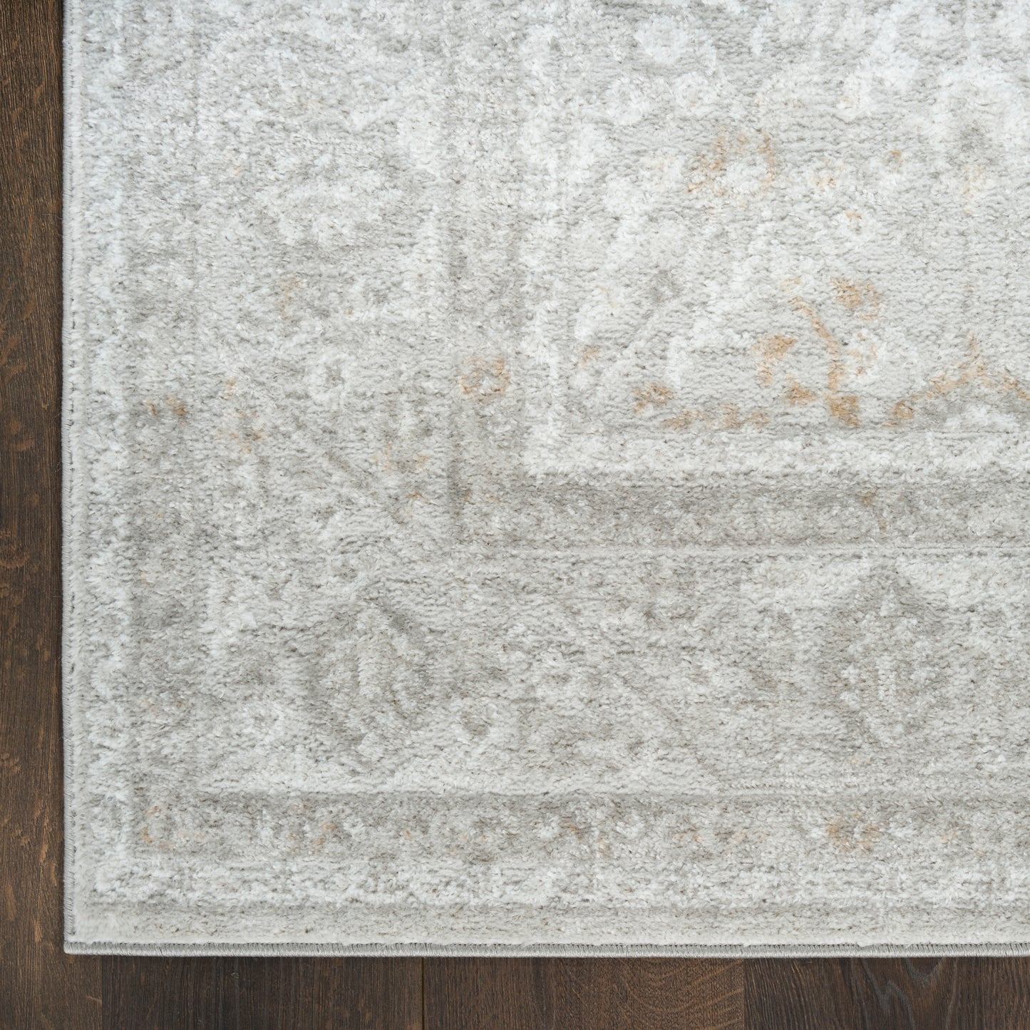 Rectangular plush gray area rug with subtle ivory traditional pattern on dark wooden floor.