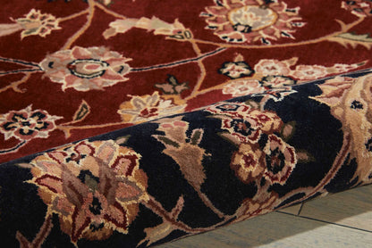 Red oriental floral rug with navy border, beige and cream blossoms; plush woven pile, rolled corner.