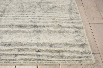 Beige-gray low-pile flat-weave rug with subtle diamond motif on light wood floor.
