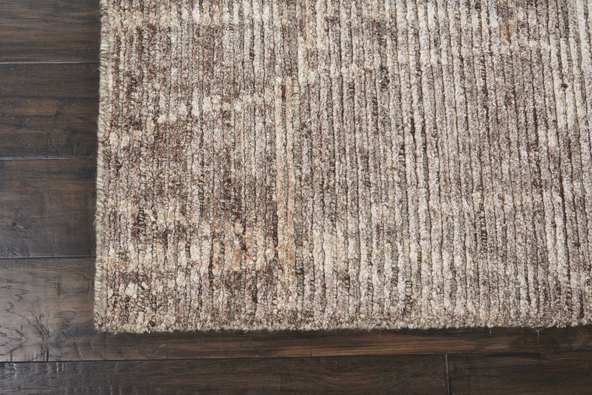 Beige brown striped textured area rug on dark hardwood floor.