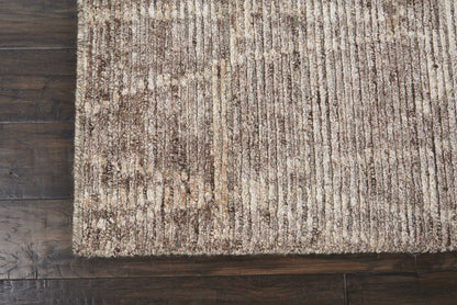 Beige brown striped textured area rug on dark hardwood floor.