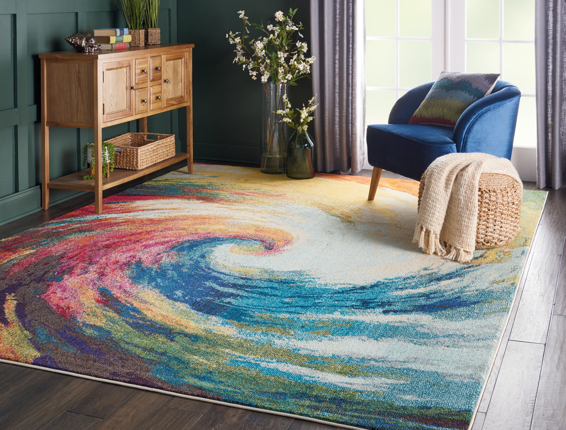 Vibrant abstract swirl rug in teal-walled living room with wooden console and blue armchair.