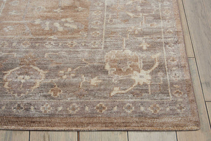 Muted floral oriental area rug with beige, taupe and brown tones, medallion motifs and decorative border on a wooden floor.