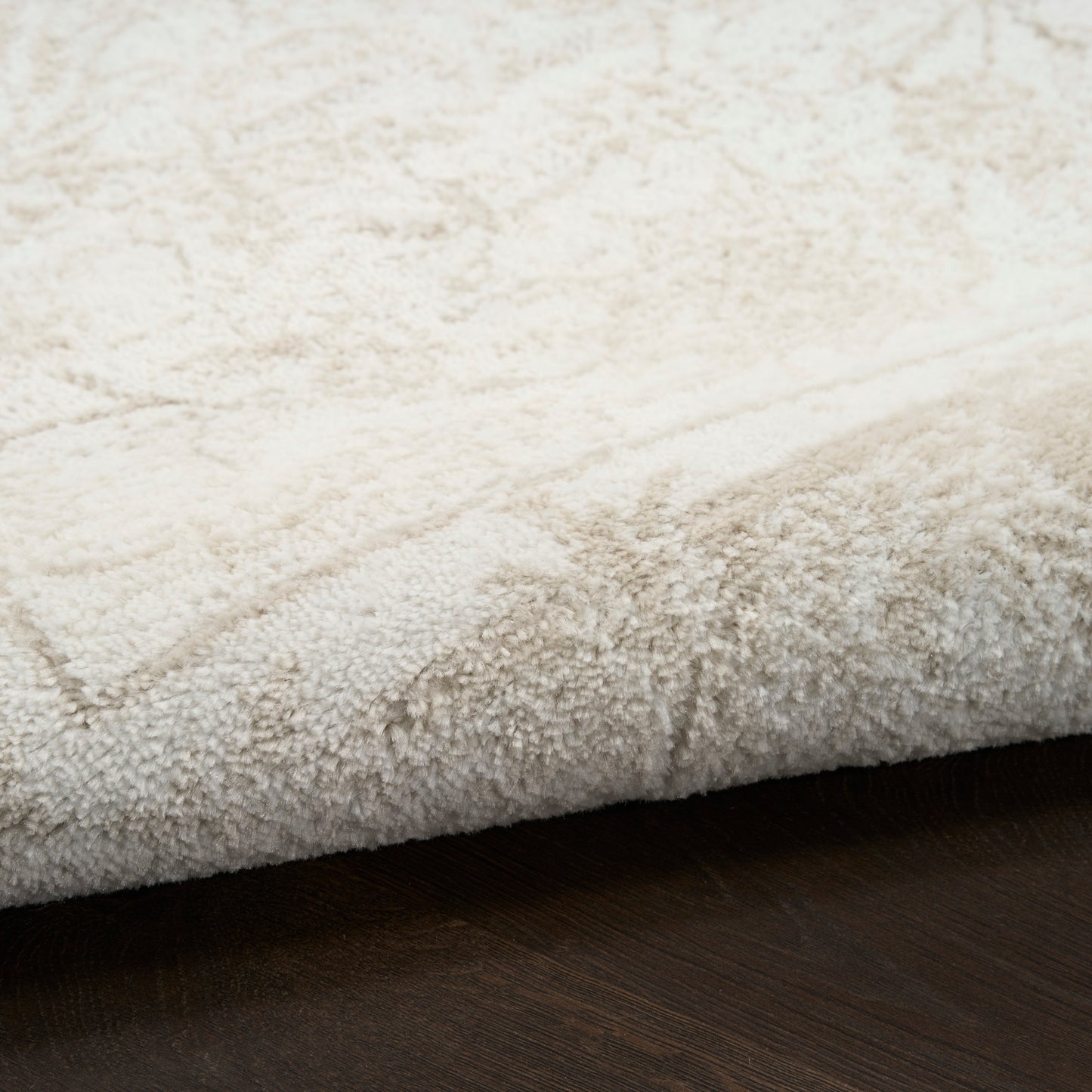 Ivory shag rug with plush pile and subtle geometric border, resting on dark wood flooring.