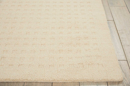 Beige shag rug with a subtle tufted grid texture on light wood floor.