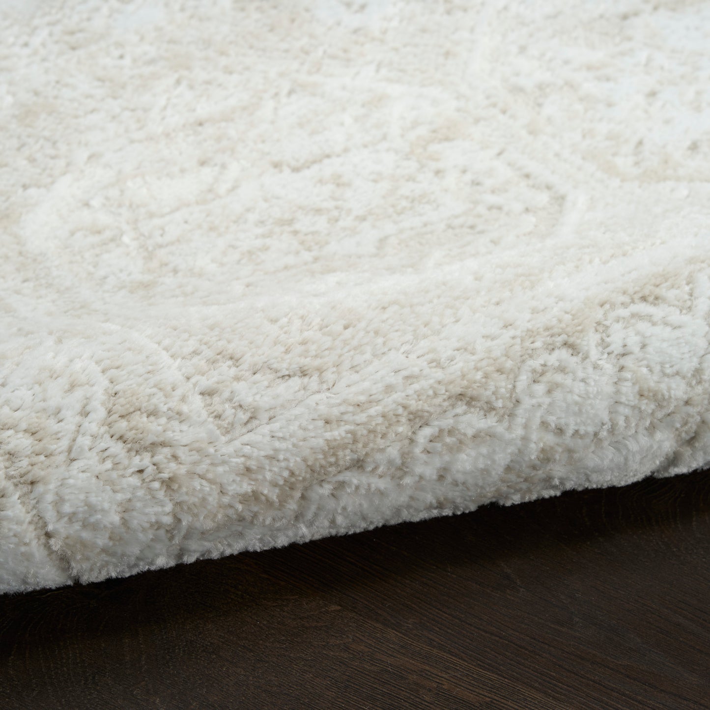 Cream fluffy shag rug with thick pile on dark wooden floor.