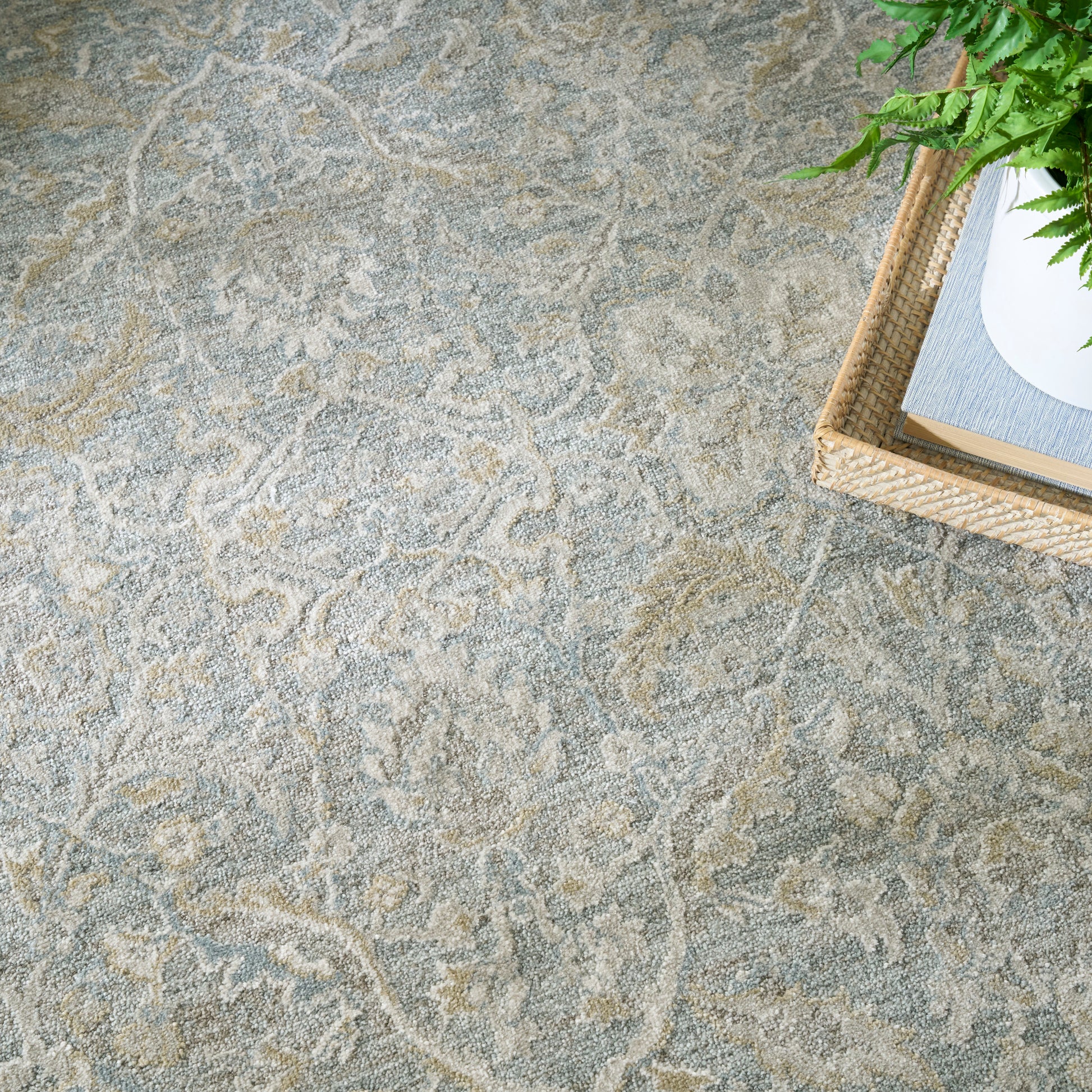 Soft gray patterned area rug with beige swirls; woven basket and green plant sit in a corner.