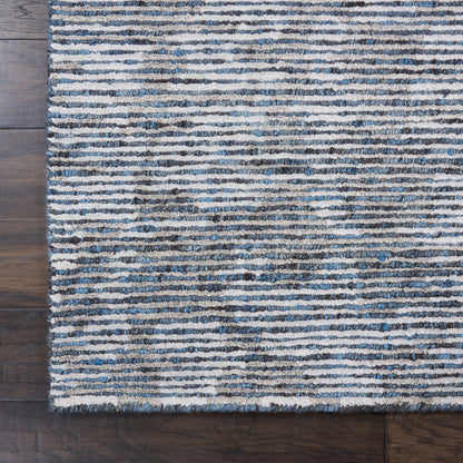 Blue and cream striped rug with textured pile on dark wood floor.