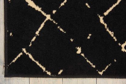 Black plush rug with cream geometric lattice/diamond trellis pattern on wooden floor.