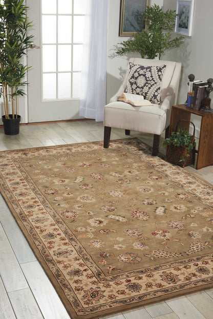 Beige traditional oriental rectangular area rug with floral motifs and ornate border on a light wood floor beside a chair.
