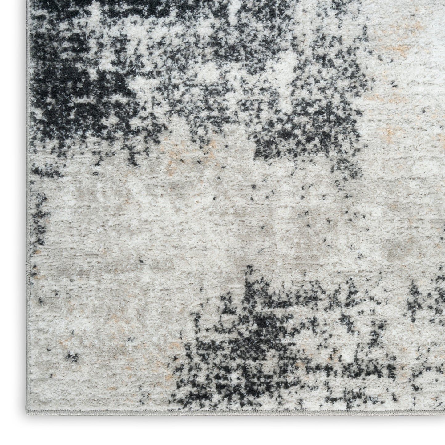 Abstract distressed beige and charcoal area rug with black speckled pattern and soft pile.