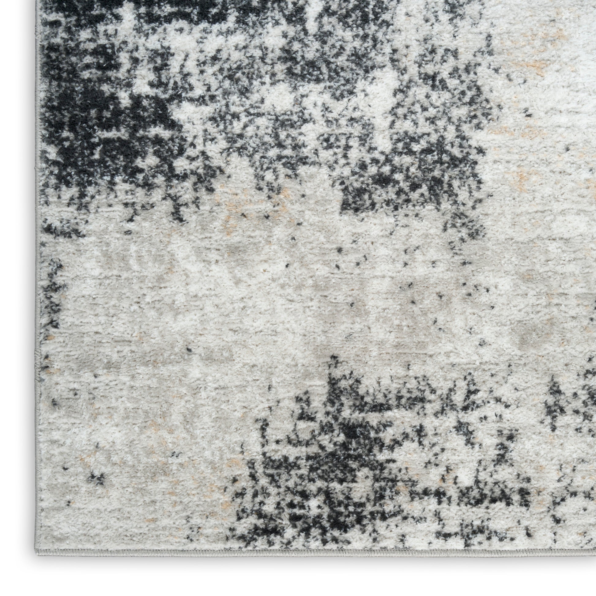 Abstract distressed beige and charcoal area rug with black speckled pattern and soft pile.