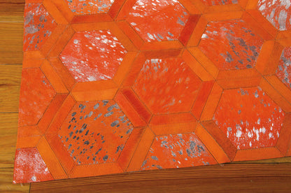 Orange hexagon patchwork rug with stitched borders and distressed speckled panels on a wooden floor.