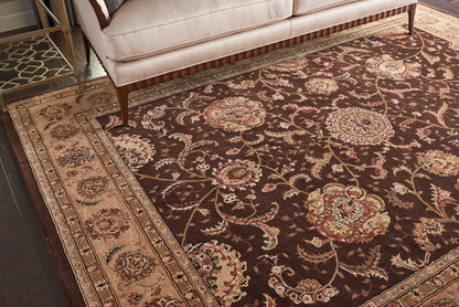 Dark brown oriental area rug with cream and beige floral medallions and ornate border under a beige sofa.