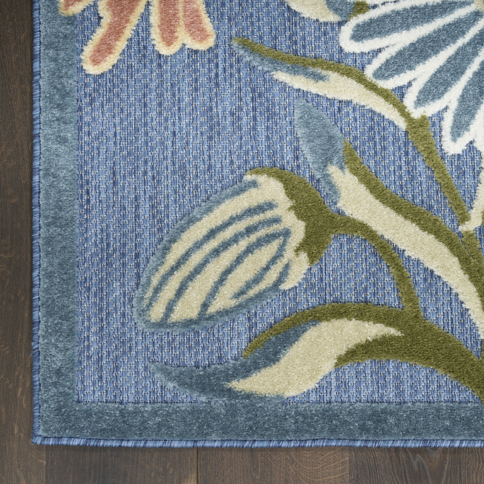 Blue botanical area rug with cream and olive-green flowers, teal border, textured woven pile.
