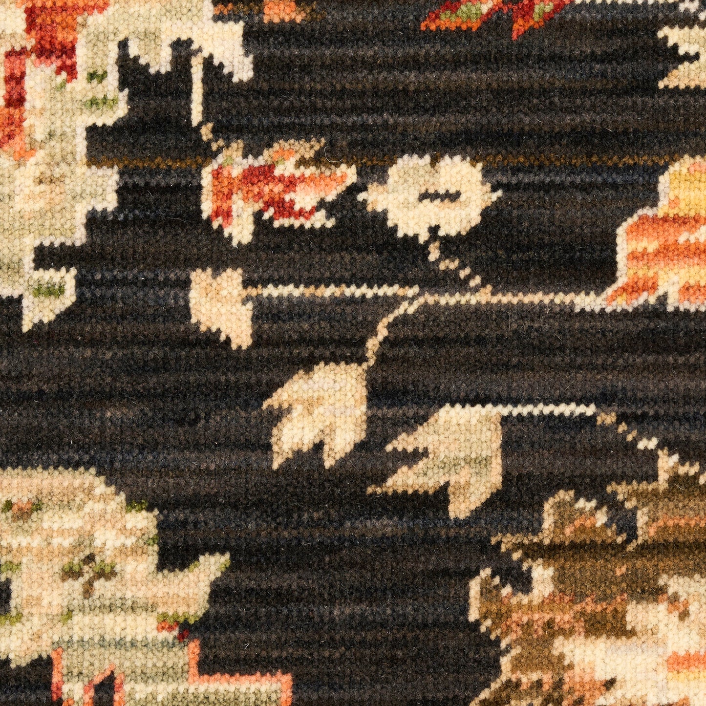Dark woven rug with cream, beige and peach floral motifs on black background; textured tufted weave.