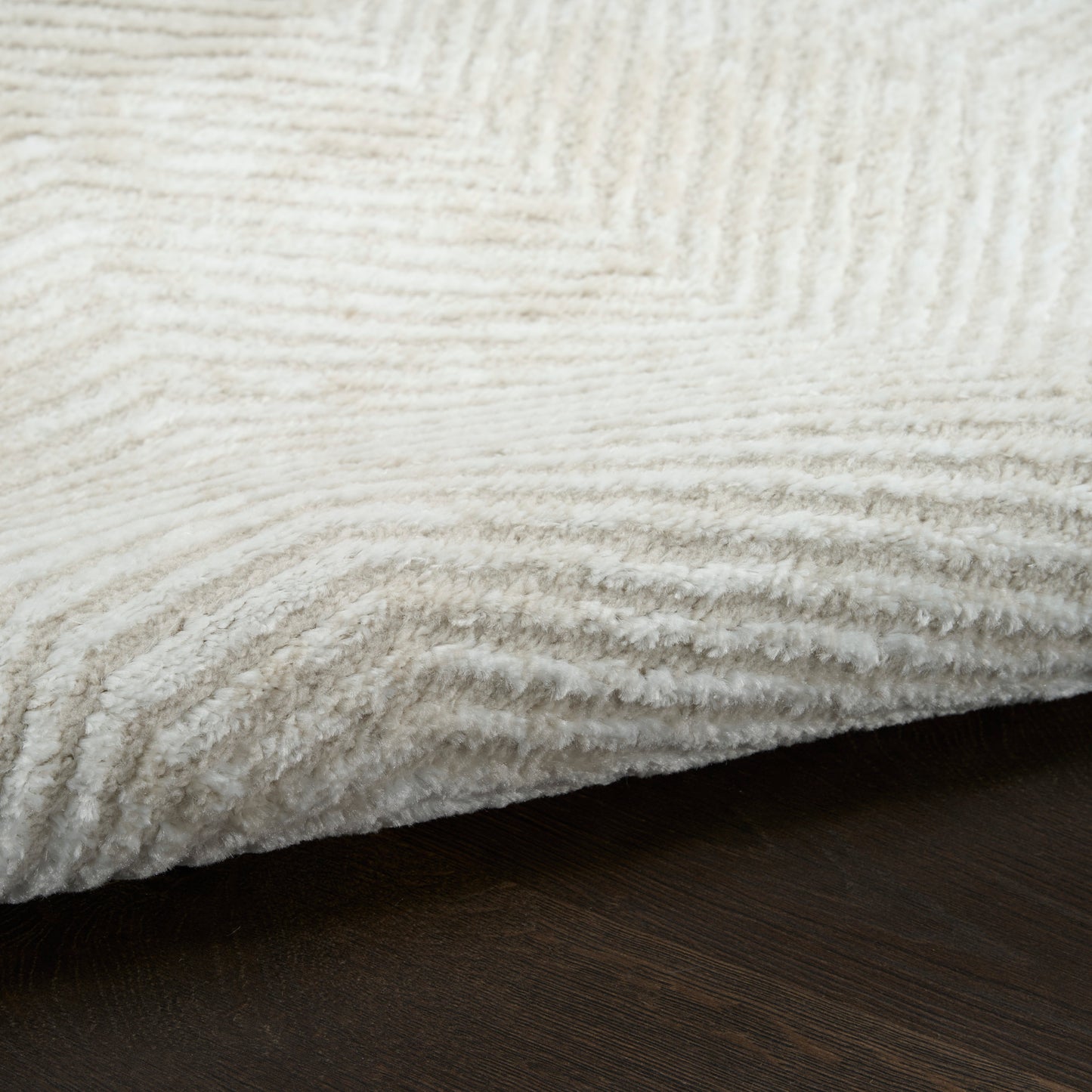 Cream shag rug with dense, plush pile on dark wood floor.