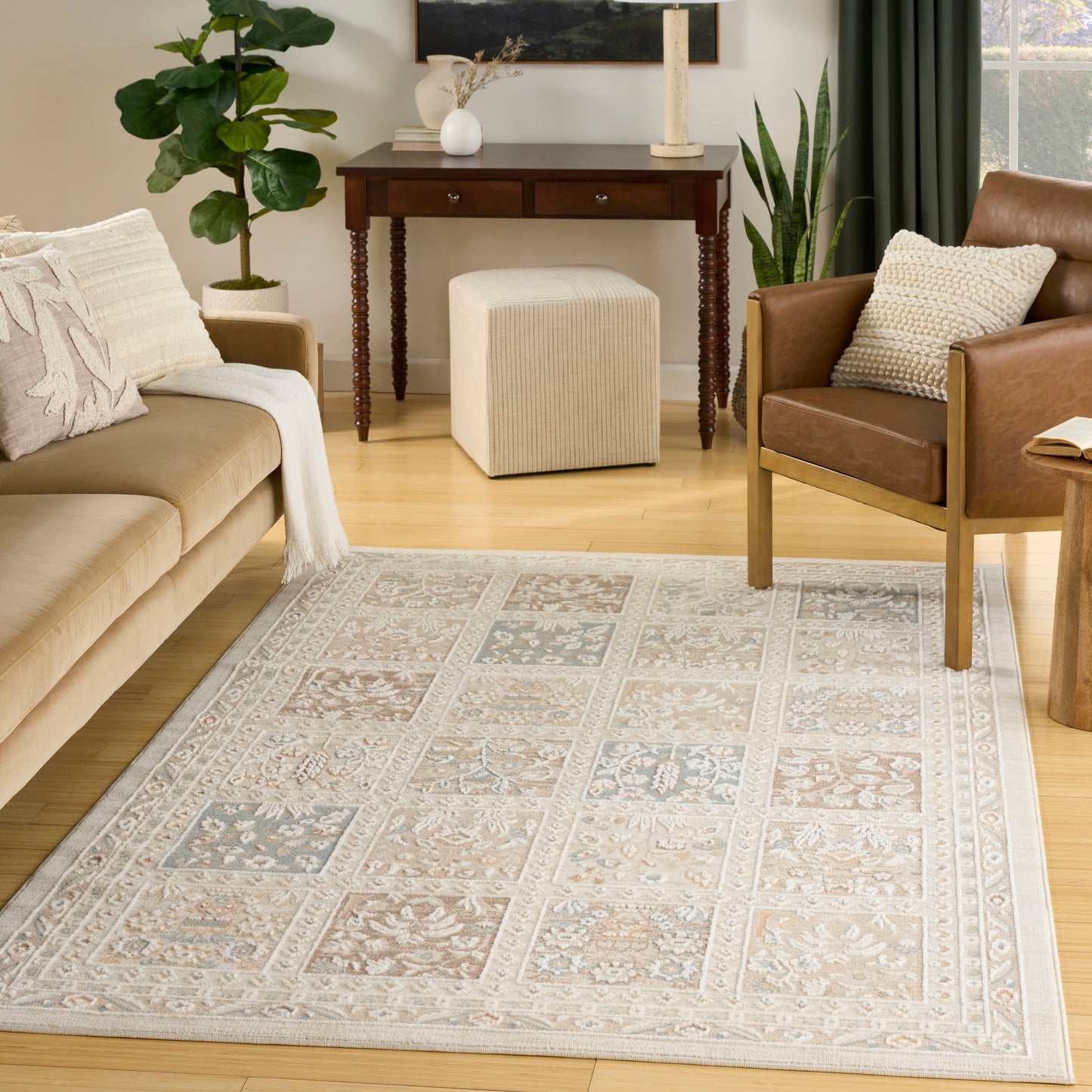 Cozy living room with a light gray-beige patterned rug, tan sofa, brown chairs, and a wooden console table.