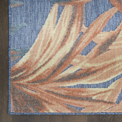 Blue textured area rug with large peach-orange leaf design, thick pile, bound edges on dark wood floor.