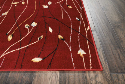 Red area rug with abstract twig pattern in white, black, tan and yellow on a wood floor.