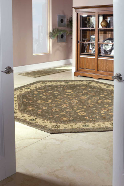 Ornate round Persian-style rug in brown, beige and gold on a light tile floor, with a wooden display cabinet nearby.