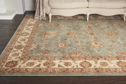 Traditional oriental area rug with a blue central field, ivory/beige border and floral motifs in a living room.
