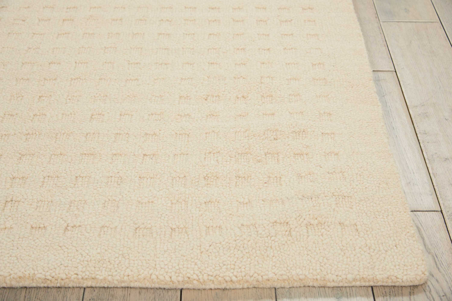 Cream shag rug with subtle square-textured pattern on light wood plank flooring.